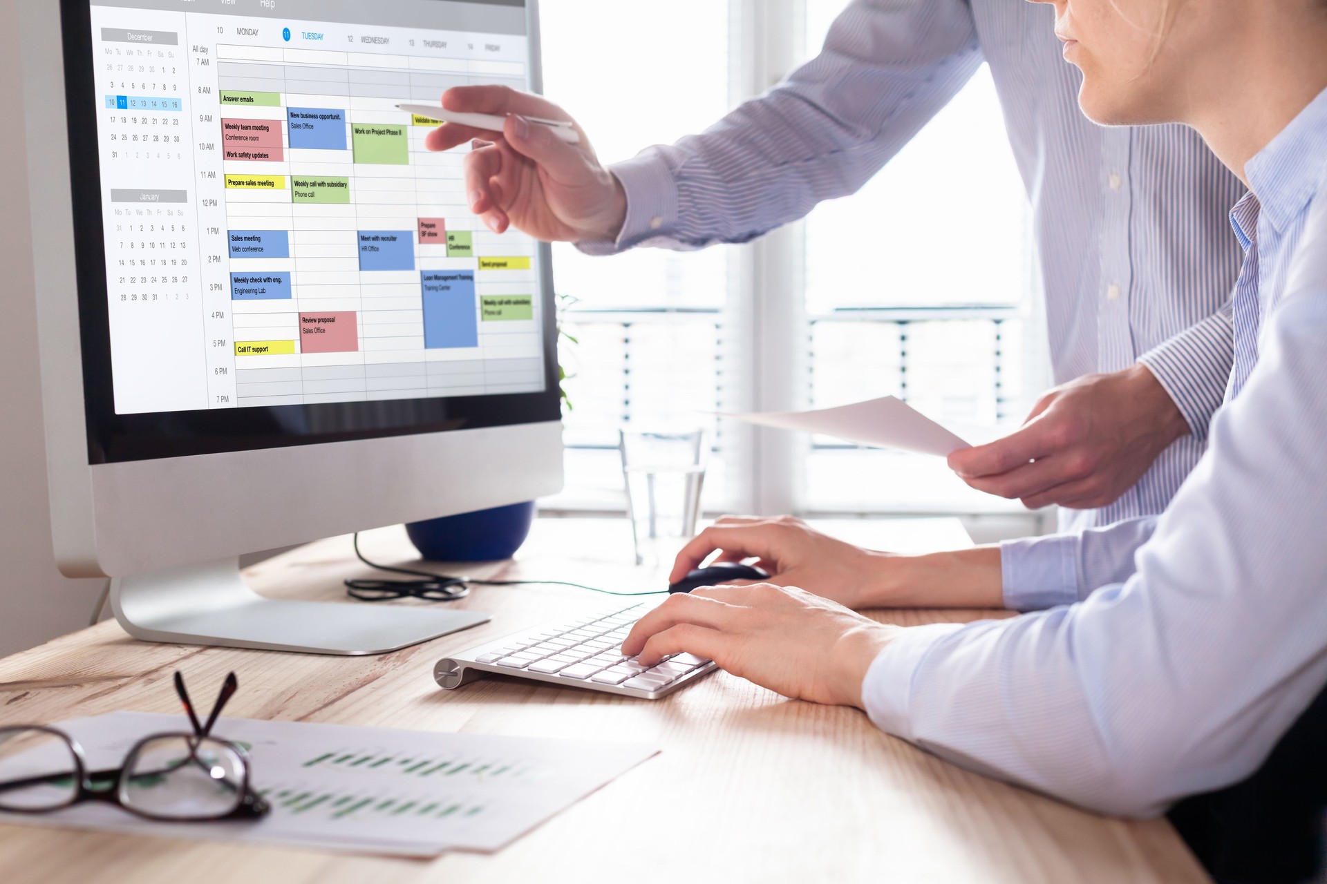Colleagues planning a meeting with calendar software on computer, search time slot between events, tasks, and appointments, busy business people using time management tool to organize work, office